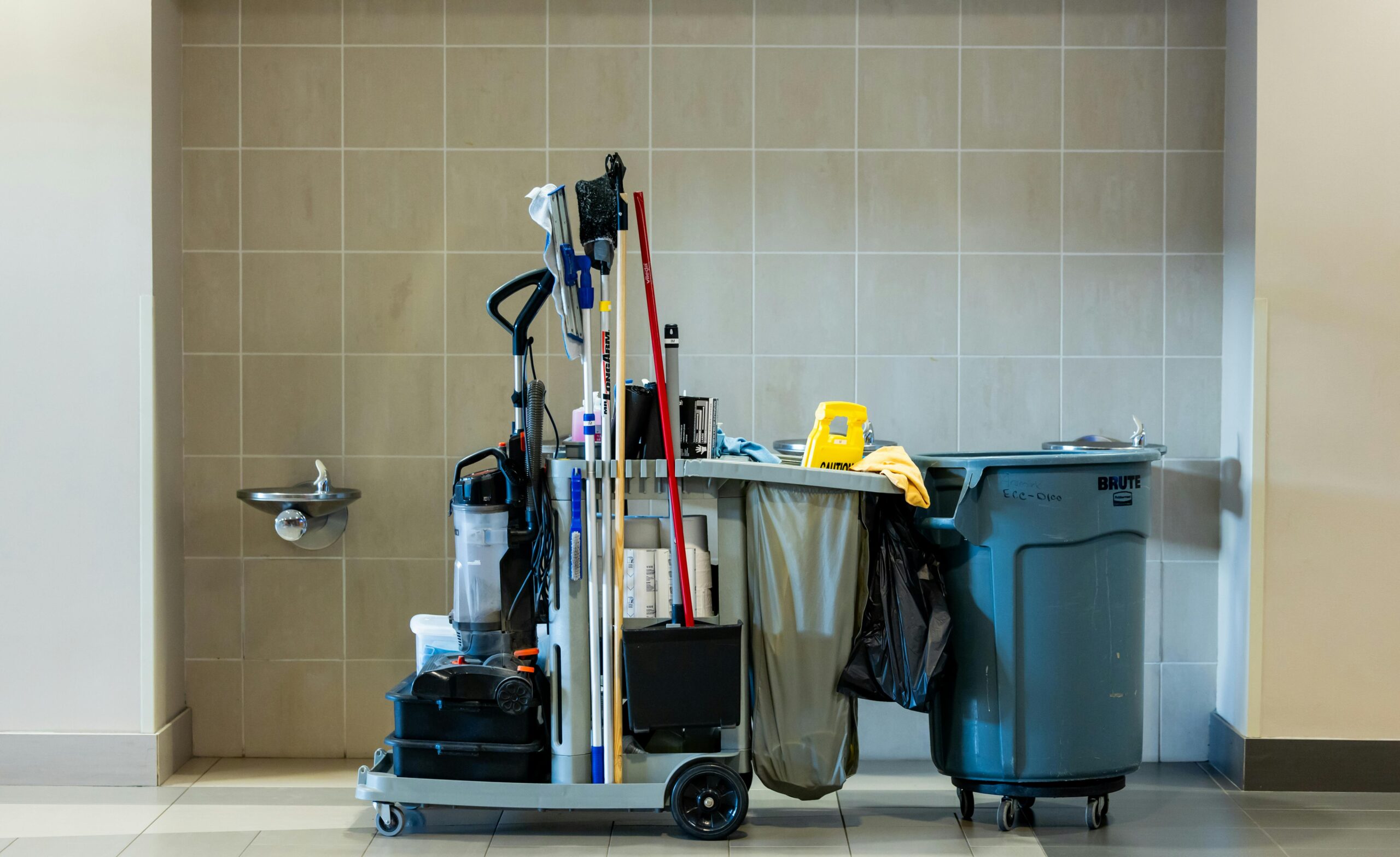 A comprehensive collection of professional cleaning tools on a cart in an indoor environment.